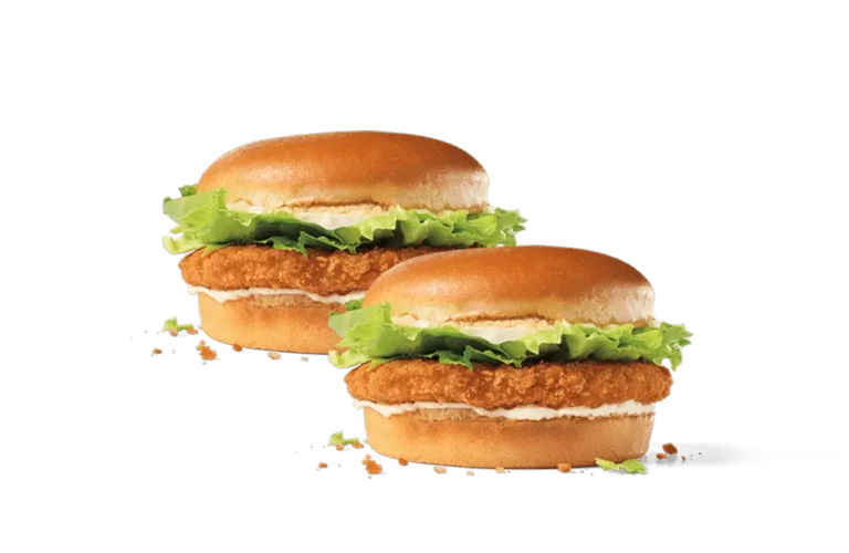 Two crispy junior chicken sandwiches featuring golden-brown breaded chicken patties, fresh green lettuce, and creamy mayonnaise on soft buns, set against a transparent background.