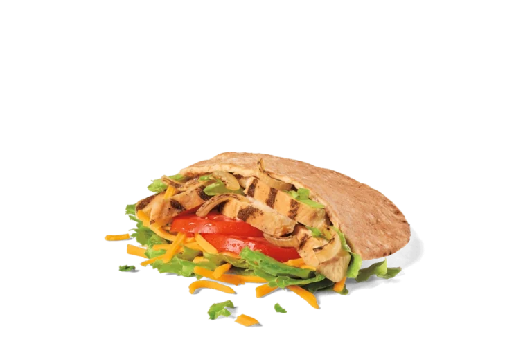 A freshly prepared chicken fajita pita sandwich overflowing with grilled chicken strips, sliced ripe tomatoes, shredded lettuce, and grated cheese, all encased in a warm, lightly toasted pita bread, presented on transparent background with scattered ingredients.