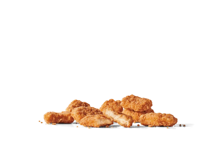 An assortment of crispy chicken nuggets with a golden-brown breading, shown in various sizes and arranged on transparent background. One of the nuggets is broken in half, revealing the tender white chicken meat inside, with small crumbs scattered around.