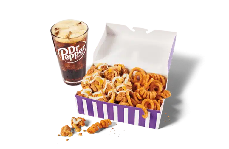 A generous portion of classic sauced & loaded popcorn chicken in a vibrant purple and white box, covered with creamy sauce and paired with crispy curly fries. Next to it is a tall glass of Dr Pepper with foam on top, all set against a clear background.