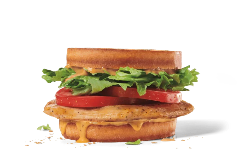 A hearty grilled chicken club sandwich featuring a seasoned grilled chicken fillet, topped with melted cheese, fresh lettuce, and juicy tomato slices between toasted bread slices, presented on transparent background with visible crumbs.