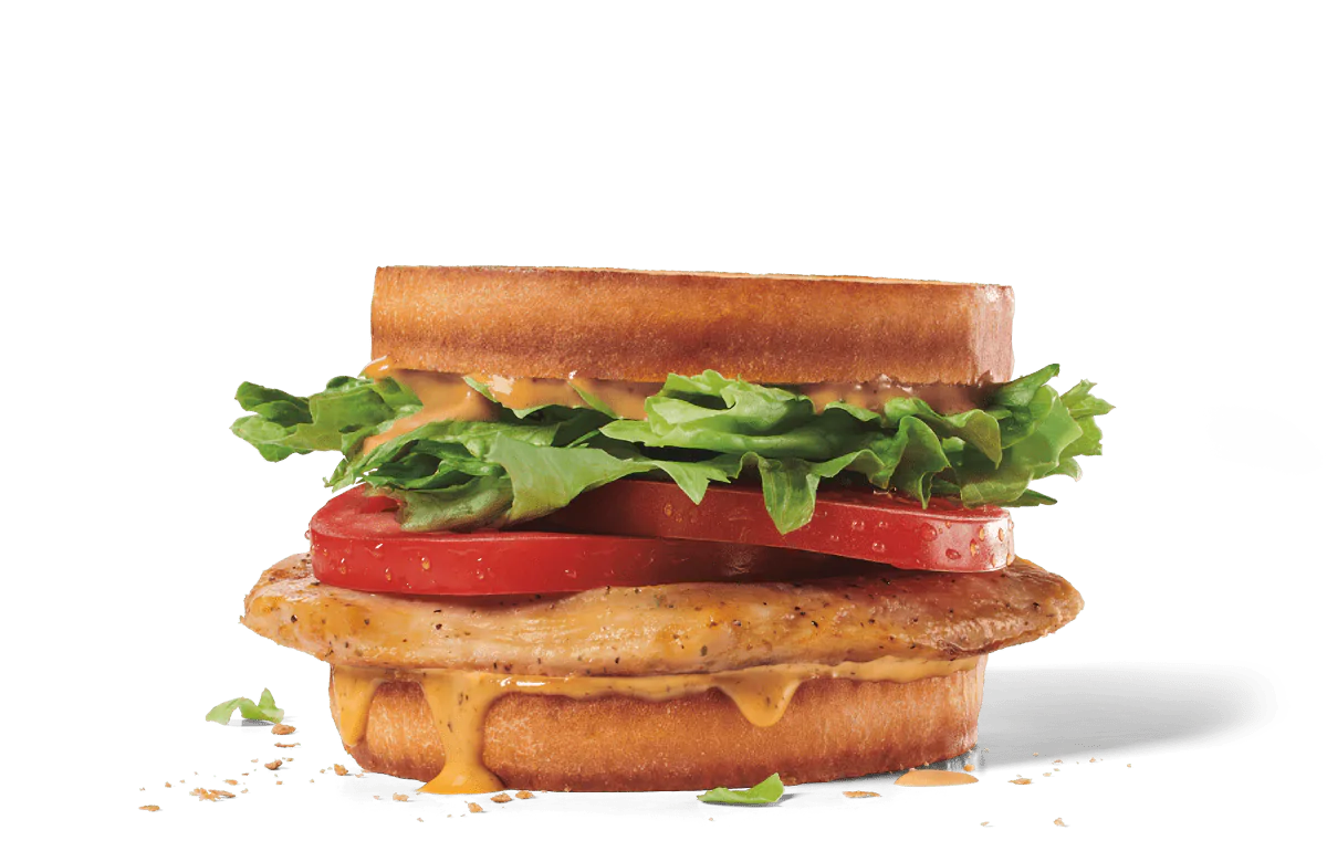 A hearty grilled chicken club sandwich featuring a seasoned grilled chicken fillet, topped with melted cheese, fresh lettuce, and juicy tomato slices between toasted bread slices, presented on transparent background with visible crumbs.