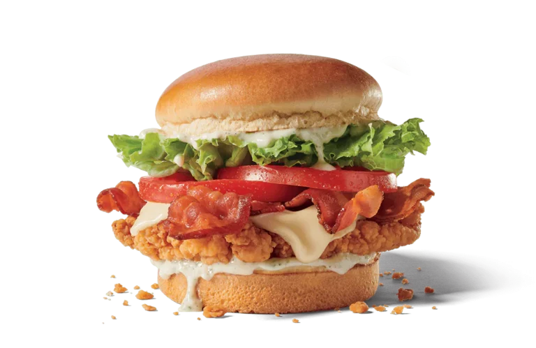A gourmet chicken club sandwich with a crispy chicken fillet, creamy ranch dressing, melted cheese, fresh lettuce, ripe tomato slices, and crispy bacon, assembled on a shiny, soft bun against transparent background with crumbs scattered at the base.