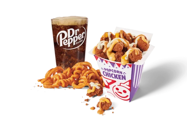 A delicious serving of spicy sauced loaded popcorn chicken in a festive red and purple striped box, drizzled with a creamy sauce, alongside a generous portion of curly fries and a full glass of Dr Pepper, set against transparent background.