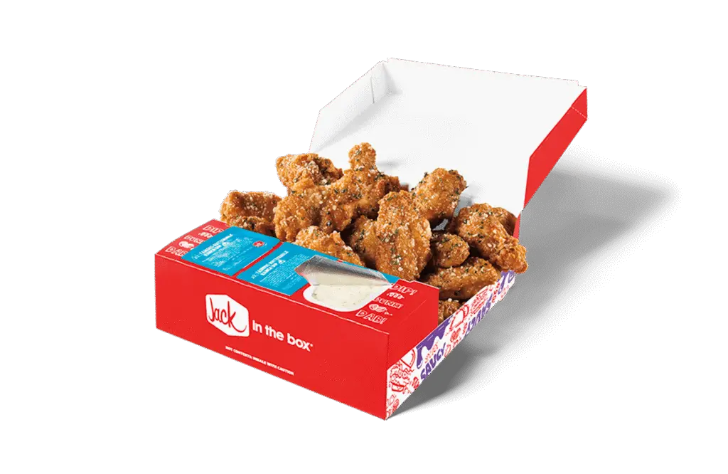 A 12-piece Garlic Parmesan Crispy Chicken Wings box from Jack in the Box, featuring crispy golden-brown wings generously coated in a flavorful garlic parmesan seasoning. The box includes a side of creamy dipping sauce and condiment packets, all packaged in a red box with the Jack in the Box logo. The open lid displays the wings for a visually appetizing presentation.