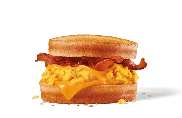 Image of a Bacon, Egg & Cheese Scrambler featuring fluffy scrambled eggs, slices of crispy bacon, and a generous helping of melted cheese, all sandwiched between two lightly toasted English muffins, with crumbs scattered around indicating a fresh, hearty meal.