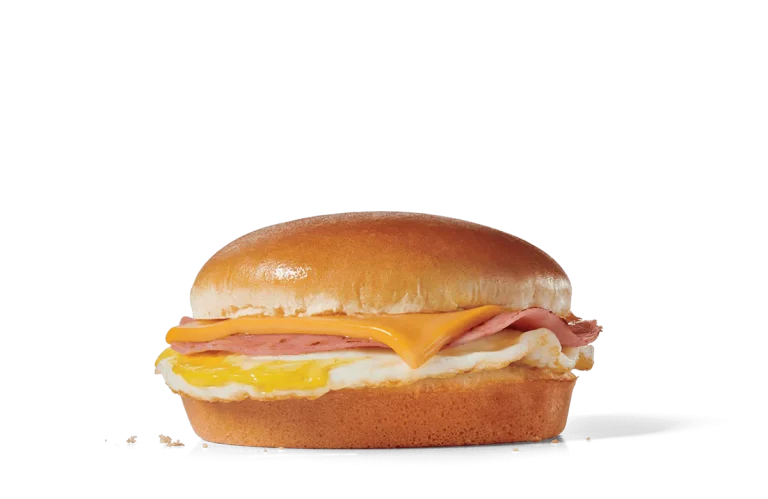 Image of a Breakfast Jack® sandwich, featuring a light, fluffy egg, a slice of ham, and melted American cheese on a soft, shiny hamburger bun.