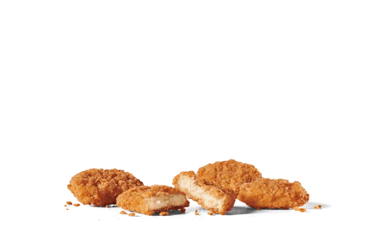A close-up view of crispy chicken nuggets scattered casually on transparent background. One nugget is broken in half, revealing the tender, white meat inside, surrounded by a golden-brown, crunchy coating. The image captures the texture and appeal of these popular bite-sized snacks, emphasizing their irresistible crunch.