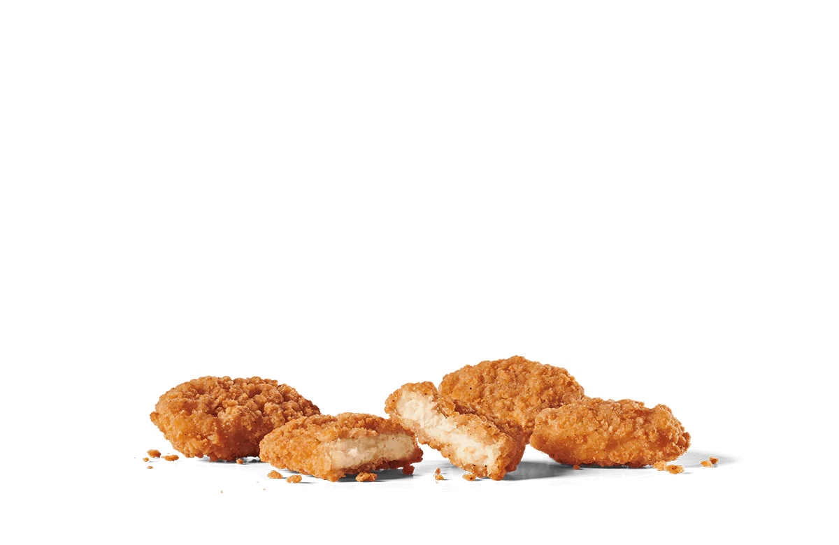 A close-up view of crispy chicken nuggets scattered casually on transparent background. One nugget is broken in half, revealing the tender, white meat inside, surrounded by a golden-brown, crunchy coating. The image captures the texture and appeal of these popular bite-sized snacks, emphasizing their irresistible crunch.