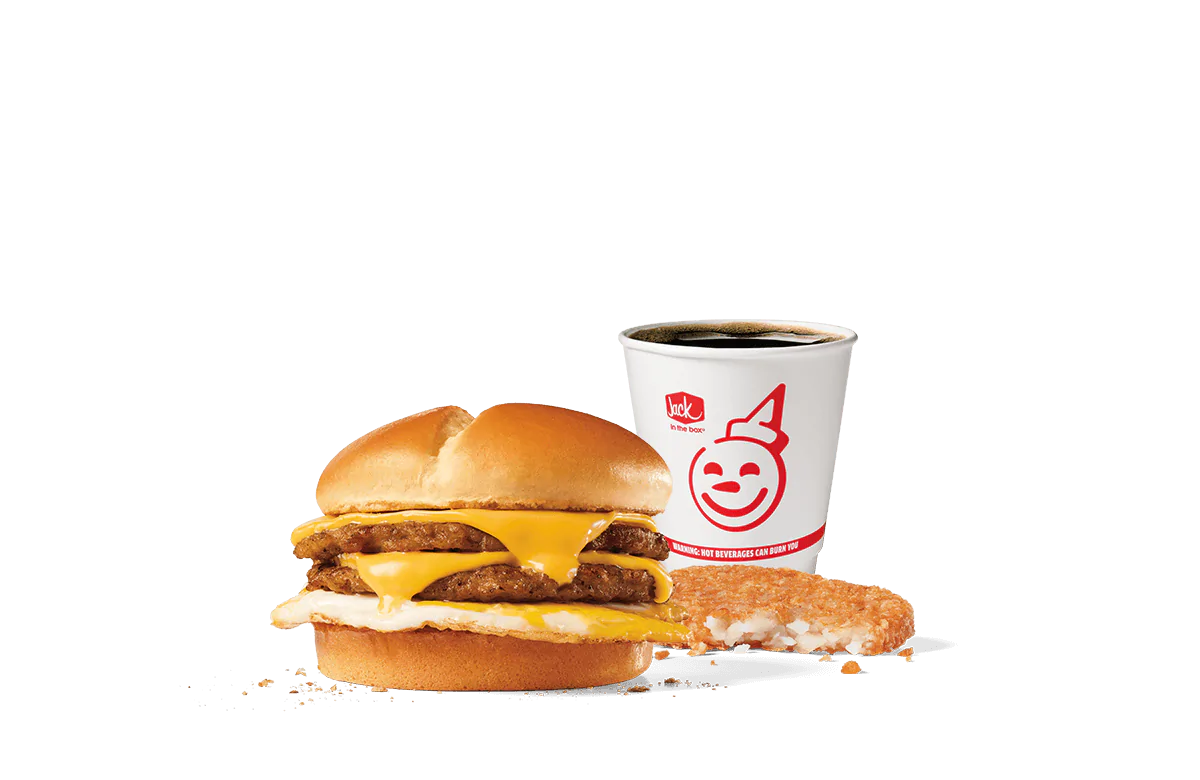 A tantalizing image of the Extreme Sausage® Sandwich Combo from Jack in the Box. The combo includes a hearty sandwich stacked with two sausage patties, egg, and melted cheese on a toasted bun, accompanied by a hash brown and a cup of hot coffee, all set against a simple, transparent background.