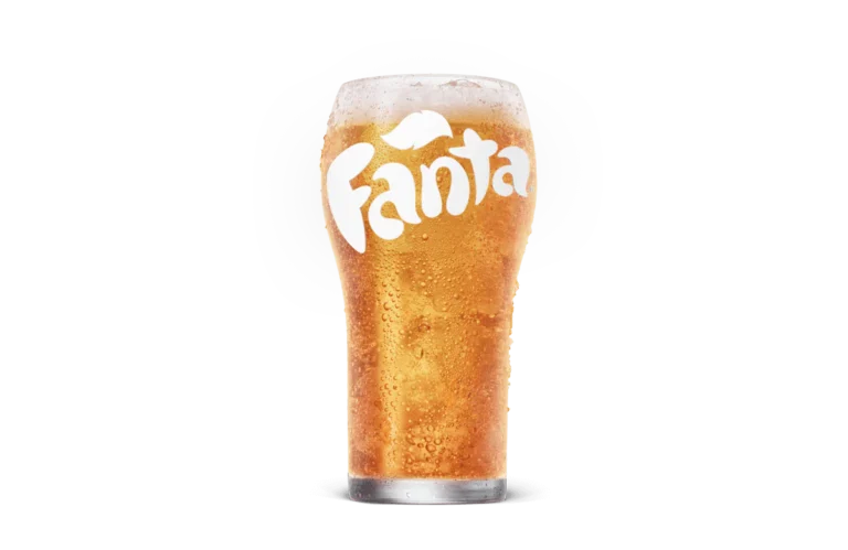 A cold glass of Fanta, showing vibrant orange soda with bubbles and the Fanta logo frosted onto the surface of the glass, set against transparent background.