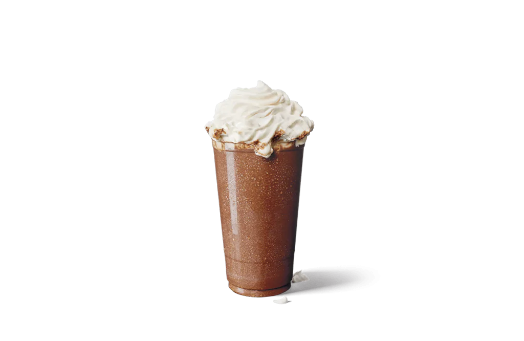 A tall glass of iced mocha creamaccino, featuring a rich chocolate hue and topped with a swirl of whipped cream. The frosty drink shows condensation on the glass, emphasizing its cold and refreshing appeal.