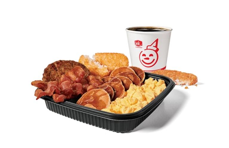 An appetizing Jumbo Breakfast Platter from Jack in the Box featuring scrambled eggs, bacon, sausage, hash browns, and mini pancakes, served with a cup of hot coffee. The meal is set against a transparent background, showcasing a hearty start to the day.