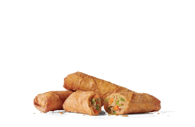 Three crispy vegetable egg rolls on transparent background. The egg rolls are golden-brown, fried to a perfect crisp, and one is cut in half, revealing a colorful filling of shredded cabbage, carrots, and other vegetables. The texture of the egg rolls is visibly crunchy with tiny golden specks.
