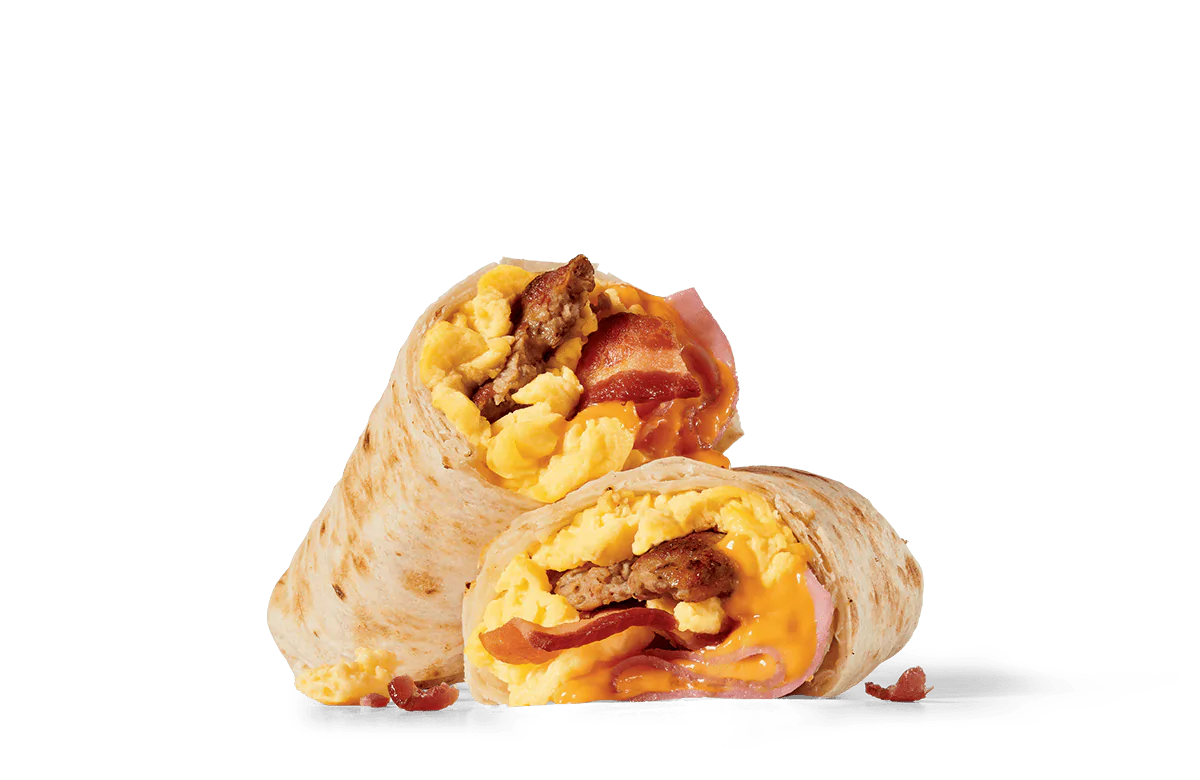 A breakfast burrito cut in half to reveal a filling of scrambled eggs, crispy bacon strips, sausage, and melted cheese, all wrapped in a toasted flour tortilla against a transparent background.