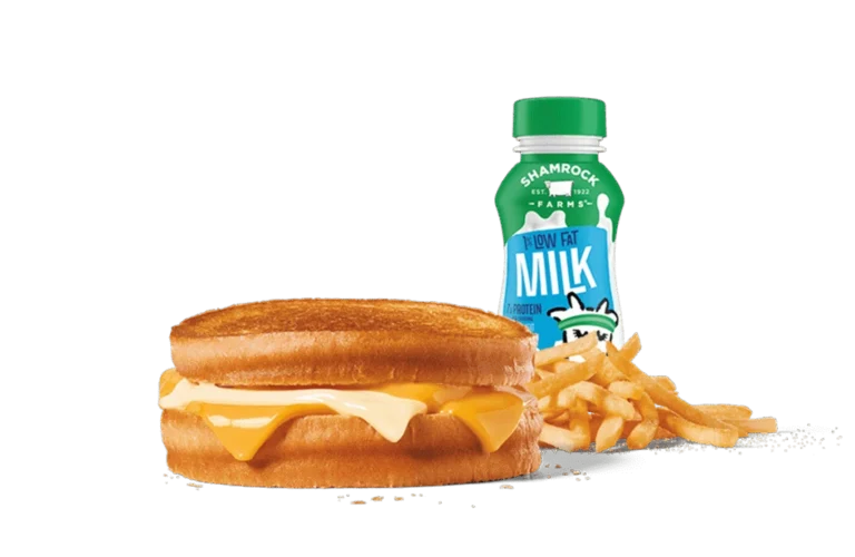 A delectable sourdough grilled cheese sandwich with melted cheese oozing out between toasted slices, paired with a side of crispy French fries and a bottle of low-fat milk. The meal is presented against a muted gray background, highlighting the golden brown crust of the sandwich and the vibrant yellow of the cheese, making it a comforting and satisfying meal choice.