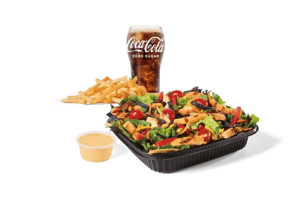 A Southwest salad topped with grilled chicken slices, served with fries, a cup of creamy dressing, and a Coca-Cola Zero Sugar drink.