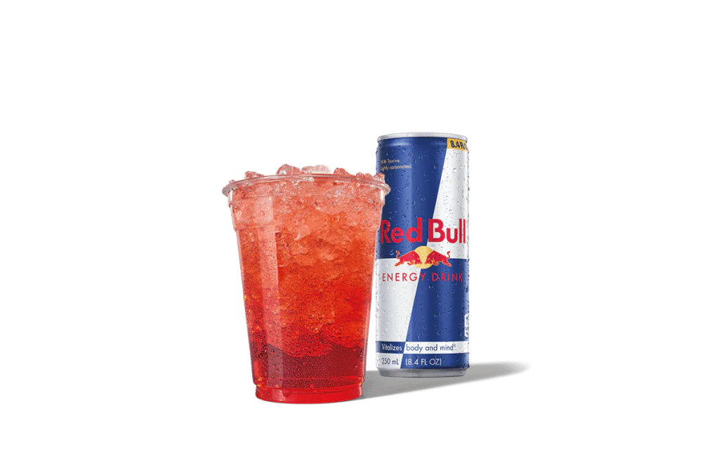 A vibrant red beverage called Strawberry Red Daze Red Bull® Infusion served in a clear cup filled with ice, accompanied by a chilled can of Red Bull® Energy Drink in the background, emphasizing energy and refreshment.