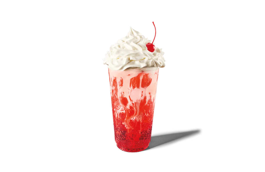 A tall glass of vibrant red soda with creamy vanilla swirls, crowned with a generous topping of whipped cream and a red cherry on top. The drink has a refreshing and indulgent appearance, perfect for a sweet treat.